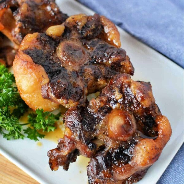 Slow cooker oxtail served on a white plate, garnished with fresh parsley for a flavorful touch.