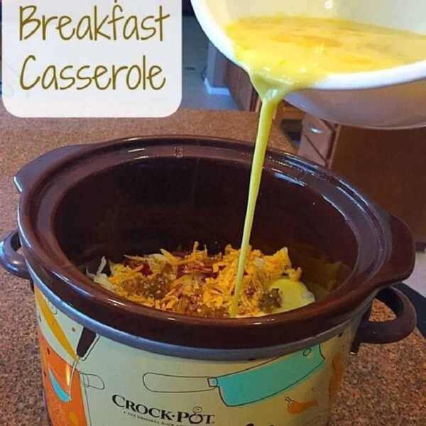 A slow cooker sits on a kitchen counter, brimming with ingredients. Beaten eggs cascade into it, mixing to perfection. In the top left corner, the text reads "Crockpot Breakfast Casserole Recipe," promising a delightful start to your morning.