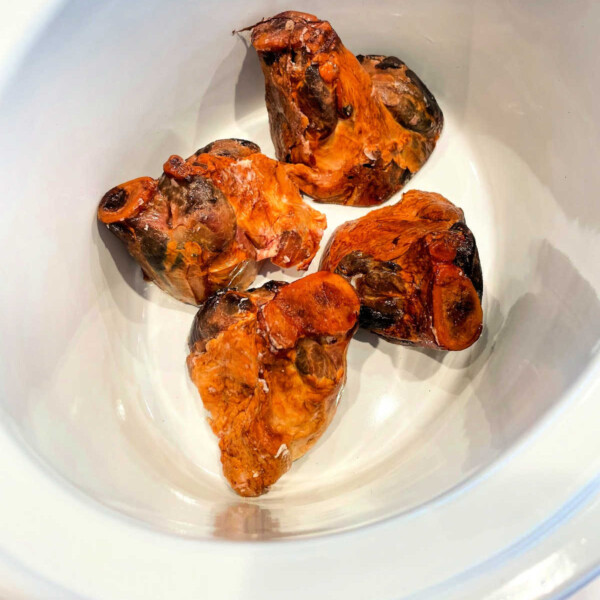 Four pieces of ham hocks gently simmering in a slow cooker.