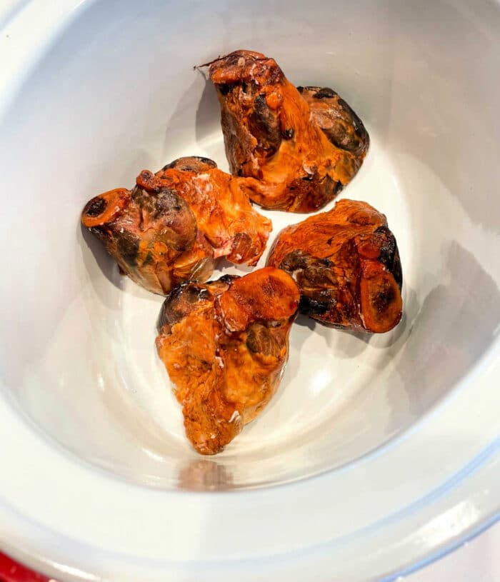 Four pieces of ham hocks gently simmering in a slow cooker.