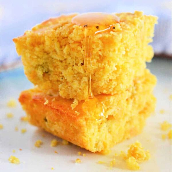 Two pieces of Jiffy Mexican Cornbread stacked on a plate, drizzled with honey.