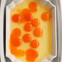 A white rectangular dish displays raw egg yolks and whites, showcasing an inviting simplicity reminiscent of no peel hard boiled eggs.