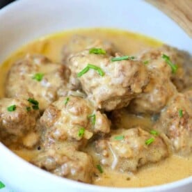 A bowl of easy homemade Swedish meatballs in creamy sauce, garnished with chopped chives, makes for a delightful dish effortlessly crafted in your Instant Pot.