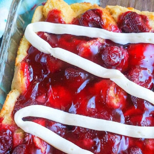 strawberry bread pudding with white icing drizzled on top in a glass dish, reminiscent of a delightful strawberry bread pudding.