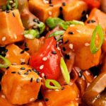 Close-up of sweet and sour tofu with bell peppers, sesame seeds, and sliced green onions, coated in a Copycat Panda Express Sweet and Sour Sauce.