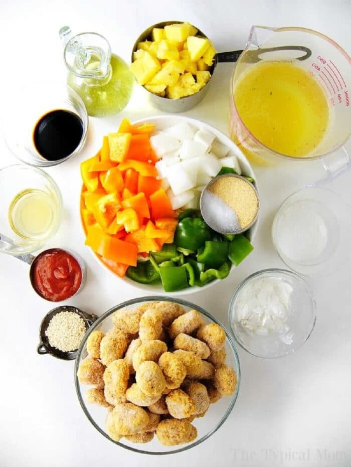 Assorted ingredients for instant pot sweet and sour chicken, including veggies, pineapple, tangy sauce, and breaded meatballs.
