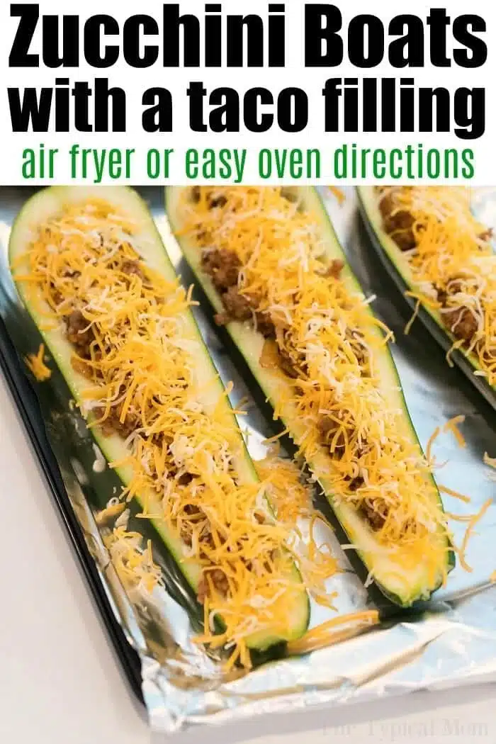 Close-up of zucchini boats filled with leftover taco meat and topped with shredded cheese on a foil-lined baking sheet. The text reads: Zucchini Boats with a taco filling - air fryer or easy oven directions.