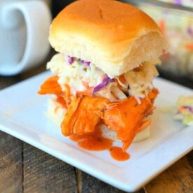 A delicious crockpot buffalo chicken slider with coleslaw graces a square white plate.