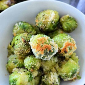 A bowl of perfectly roasted Brussels sprouts, skillfully transformed from their frozen state, is topped with golden breadcrumbs and flavorful seasoning.