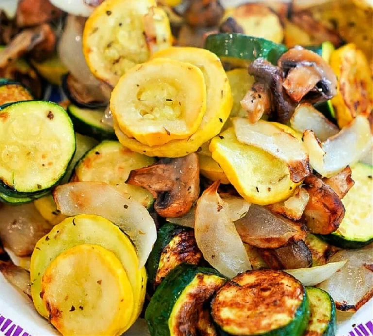 A dish featuring air fryer vegetables, including sautéed yellow squash, zucchini, mushrooms, and onions. The sliced veggies are seasoned to perfection with a delightful browning from cooking. This colorful mixture is beautifully presented on a plate.