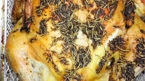 Roasted from frozen whole chicken with herbs on a metallic tray, capturing the essence of a perfectly baked delight straight from the oven.