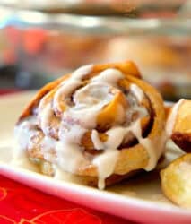 A close-up of Bisquick Cinnamon Rolls topped with icing on a white plate.