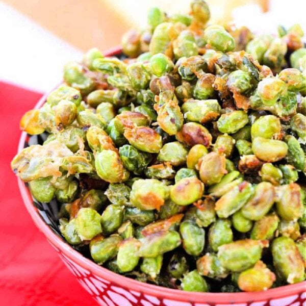 A bowl of roasted, dried edamame sits elegantly on a red cloth.