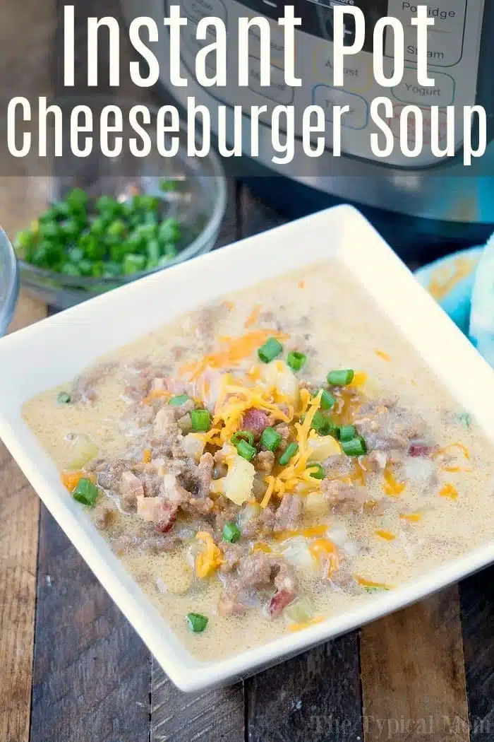 A square white bowl cradles a hearty instant pot cheeseburger soup, brimming with ground beef, melted cheese, diced tomatoes, and fresh green onions. In the background, chopped green onions await in a clear bowl beside the familiar curves of an Instant Pot.