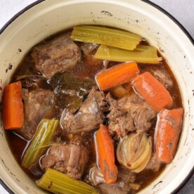 A pot filled with braised turkey necks, carrots, celery, and onions in a savory broth, with hints of flavor reminiscent of boiled turkey necks.