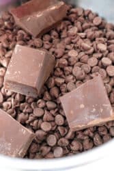 Chocolate chips and chunks of chocolate bar in a bowl, perfect for making fudge with peanut butter and condensed milk, ready for melting or mixing.