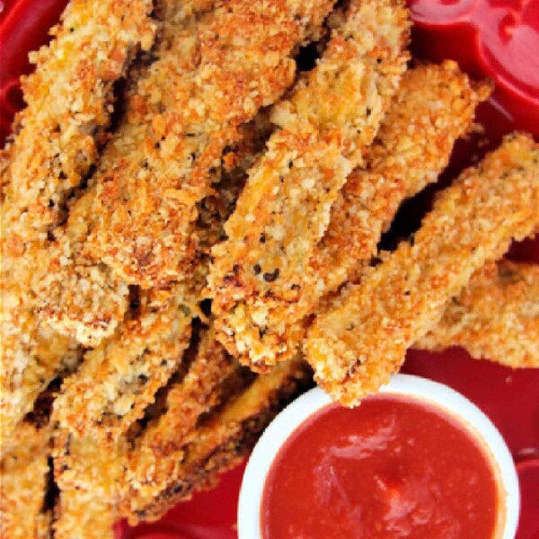 Plate of crispy breaded eggplant fries with a side of red dipping sauce.