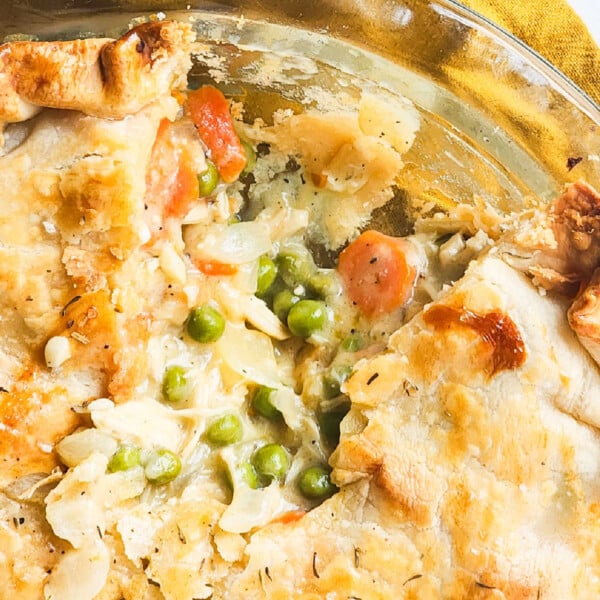 A close-up of a leftover turkey pot pie with a flaky crust reveals carrots, peas, and a rich filling without cream of chicken.