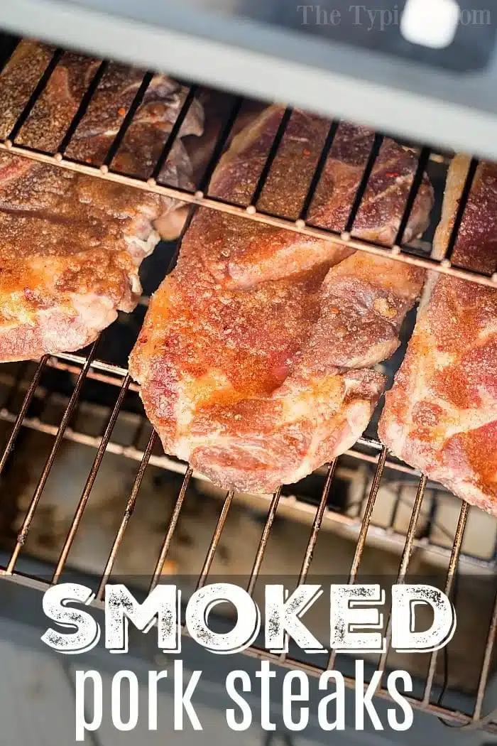 Four large pork steaks, perfectly seasoned, sizzle on a wire rack inside the smoker. The caption at the bottom proudly announces: SMOKED pork steaks.