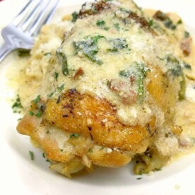 A creamy chicken dish sits elegantly on a white plate, showcasing stuffed chicken breast alongside tender instant pot chicken thighs, bone-in, with a fork subtly placed in the background.