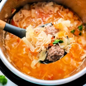 A spoonful of hearty, old-fashioned cabbage soup with tender meatballs and fresh vegetables simmering in a pot.