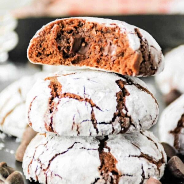 Three brownie mix crinkle cookies are stacked, with the top one broken in half to reveal a soft, fudgy interior.