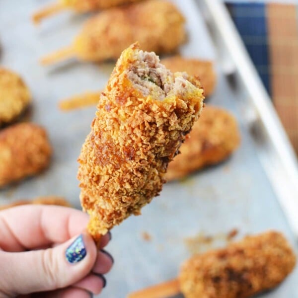 A hand holds a breaded, fried mock chicken with a bite taken, revealing the savory interior reminiscent of mock chicken legs.