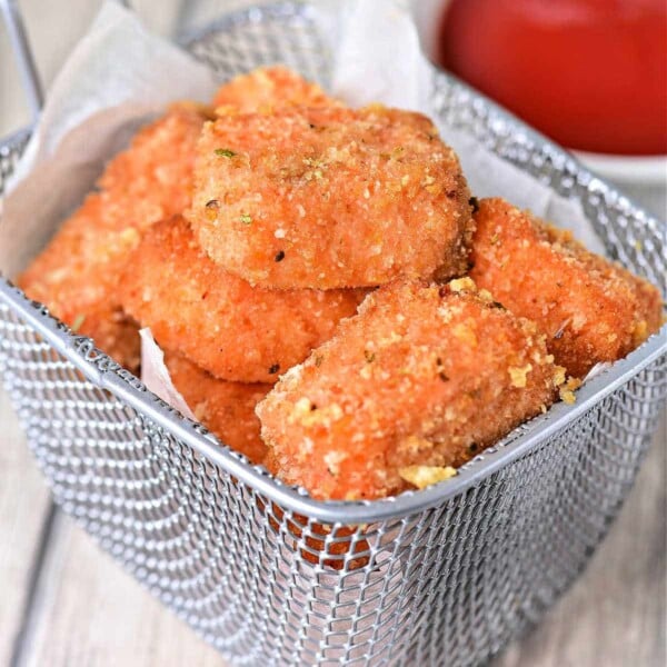 Golden succulent salmon bites, while a bowl of ketchup waits eagerly in the background.