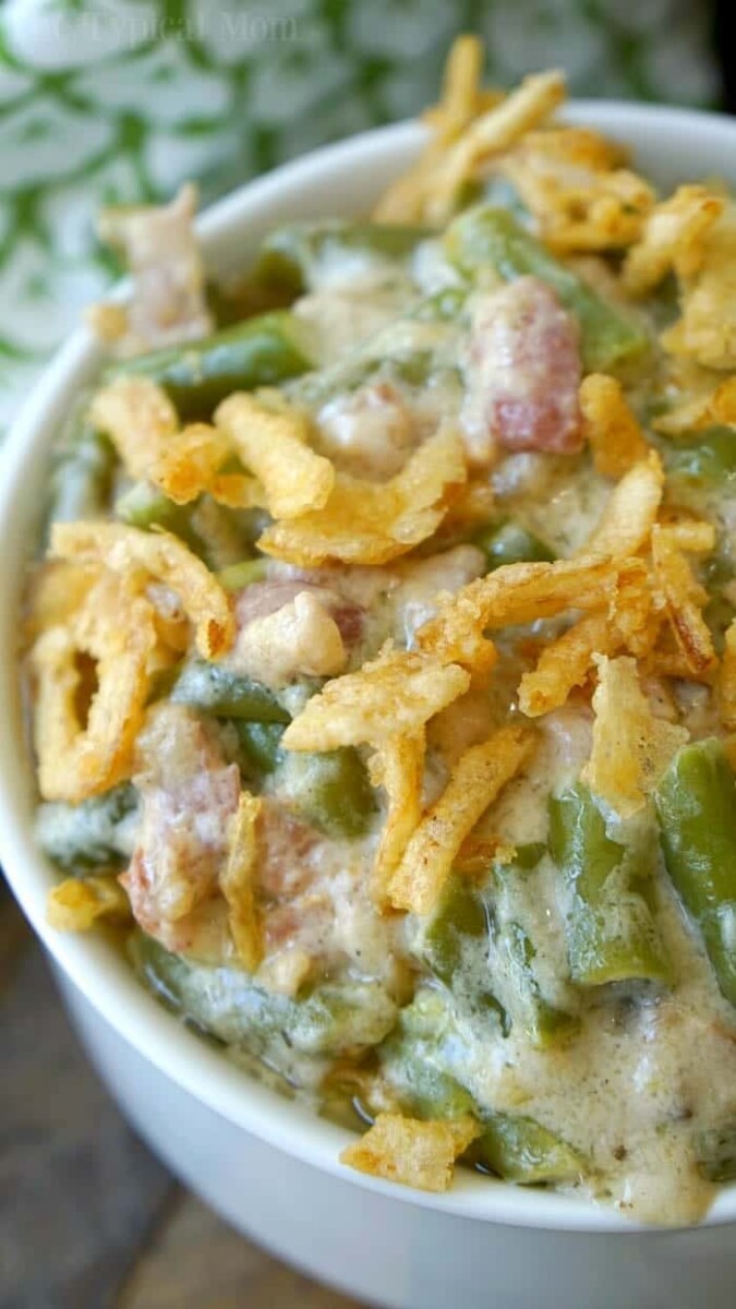 Close-up of an instant pot green bean casserole, topped with crispy fried onions, served in a white bowl.