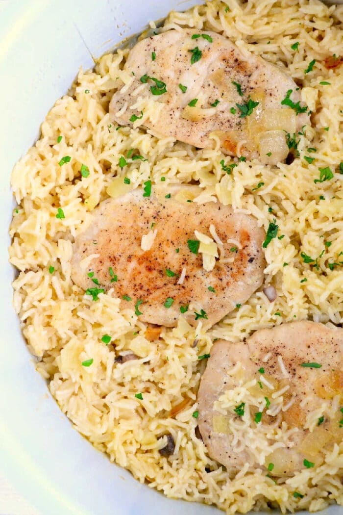 pork chops on a bed of seasoned rice, garnished with chopped parsley—a perfect meal to enjoy alongside ninja foodi pork chops.
