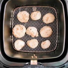 Air fryer scallops are seasoned with pepper and arranged in a single layer inside the air fryer basket for perfect, tender results.