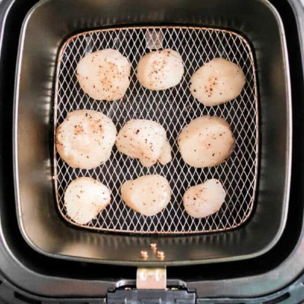 Air fryer scallops are seasoned with pepper and arranged in a single layer inside the air fryer basket for perfect, tender results.