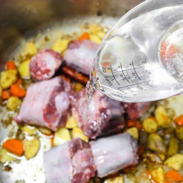 Learn how to make pho broth by pouring water into a pot filled with succulent meat, fresh carrots, and hearty potatoes.