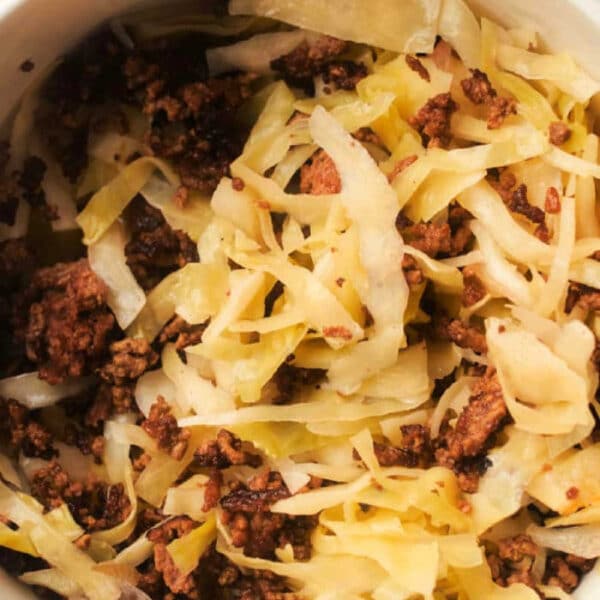 Bowl of cooked ground beef mixed with sautéed cabbage strips on a white surface, perfect for a quick Sauerkraut Recipe with Meat twist.