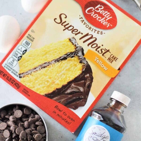 Betty Crocker yellow cake mix cookies crafted with eggs, chocolate chips, vanilla, and oil rest on a white surface.