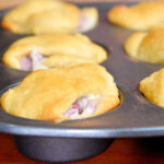 Golden brown crescent roll sandwiches baked in a muffin tin, with filling visible at the edges—a perfect leftover ham recipe for easy, savory snacks.