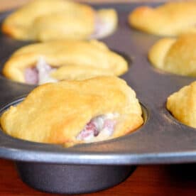 Golden brown crescent roll sandwiches baked in a muffin tin, with filling visible at the edges—a perfect leftover ham recipe for easy, savory snacks.