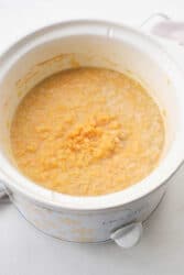 Close-up of a slow cooker with creamy yellow oatmeal inside, perfect for those mornings when you need a warm and cozy start. This versatile appliance can also craft delectable lentils, bringing comforting flavors to your table.