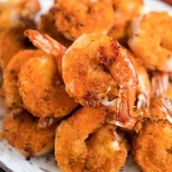 A plate of golden-brown, crispy air fryer fried shrimp stacked in a pile, showcasing a crunchy texture with visible seasonings.