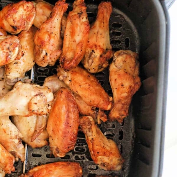 Cooked lemon pepper chicken wings in an air fryer basket.