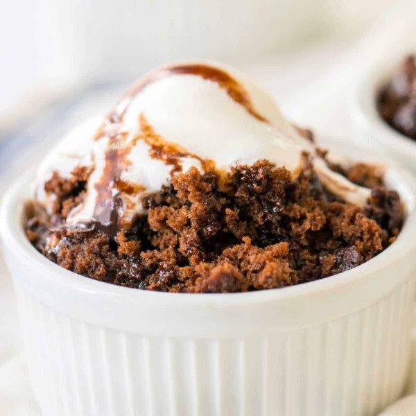 A hot water chocolate cake, baked to perfection in a white ramekin, is crowned with melting vanilla ice cream and draped in luscious chocolate sauce.