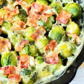 Creamy Brussels sprouts with cream and crispy bacon sizzle in a cast iron skillet.