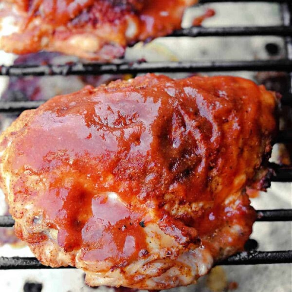 Smoked chicken breast covered in barbecue sauce is grilling on the barbecue grate.