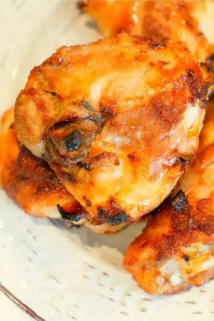 Close-up of a plate holding several pieces of cooked and browned chicken, suggesting they have been baked or grilled for about 45-50 minutes—ideal if you’re wondering how long to bake bone-in chicken thighs at 350 degrees. The chicken appears golden and crispy, with some charred edges.