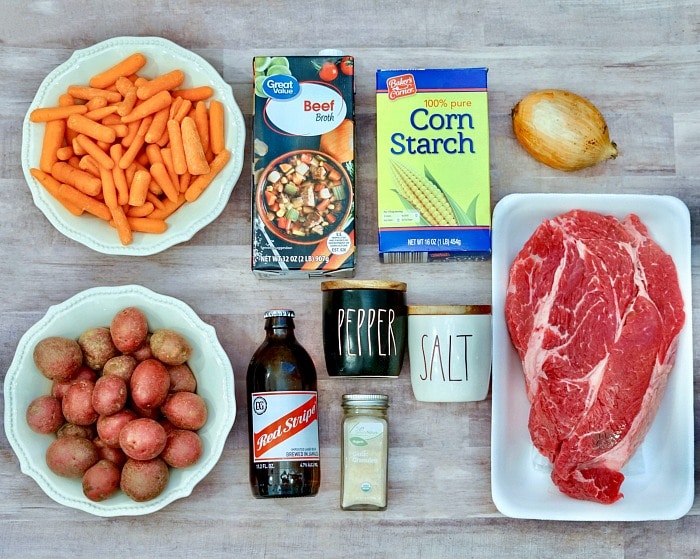 Raw pot roast ingredients: carrots, potatoes, beef broth, beer, cornstarch, onion, spices, and a raw beef roast&mdash;perfect for making a flavorful roast with onion soup mix in crockpot.