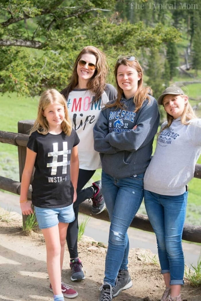 Four people posing casually outdoors by a wooden fence with lush greenery in the background, perhaps discussing how to start homeschooling.