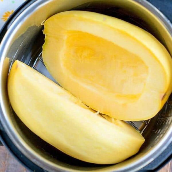 Halved spaghetti squash, a summer favorite in July instant pot recipes, sits ready on a wooden surface.