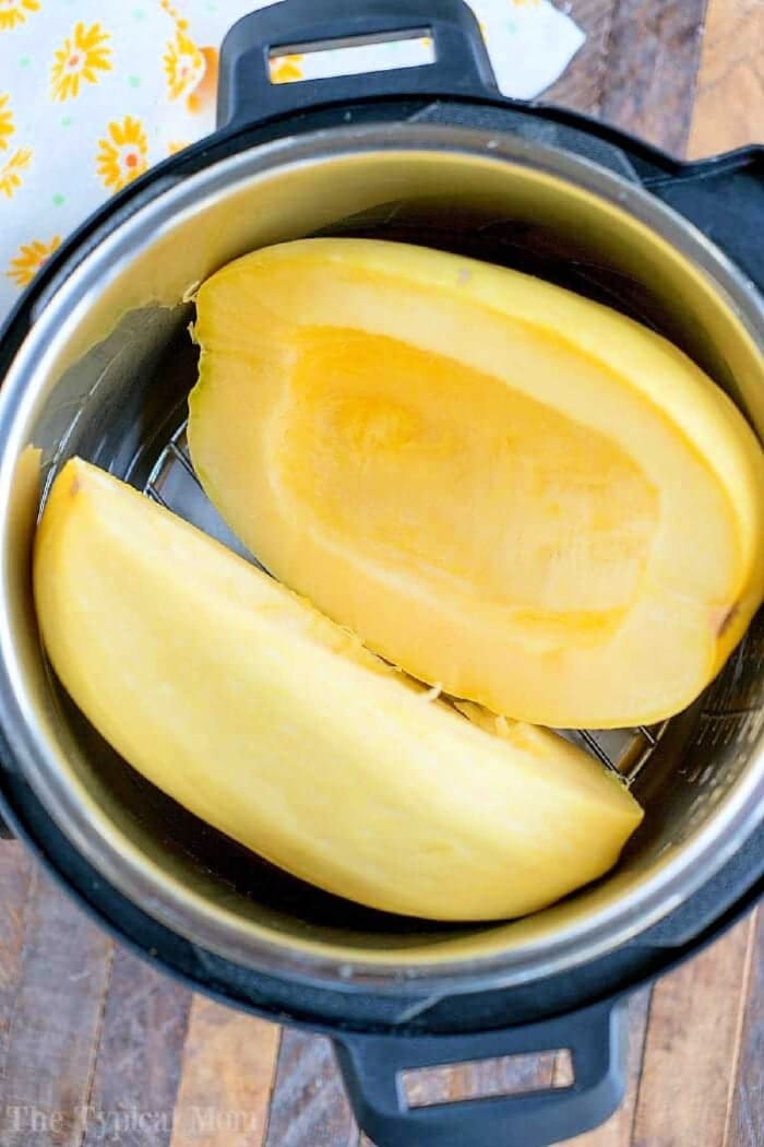 Halved spaghetti squash, a summer favorite in July instant pot recipes, sits ready on a wooden surface.