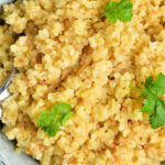 A bowl filled with cooked bulgur wheat garnished with green herbs. The text overlay on the image reads, "How to Cook Bulgur Wheat on the stove, in microwave, in pressure cooker.