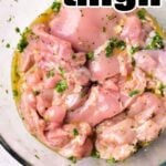 A glass bowl is filled with raw chicken thighs marinating in a Mediterranean mixture of herbs and oil. The text “Mediterranean Chicken Marinade” is written in large, bold letters at the top and bottom of the image.